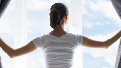 start early - woman opening curtains on morning sky