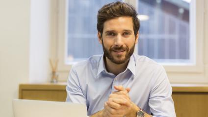 Male employee with beard looking at camera with hands folded - real person employee profile to personalize HR communication